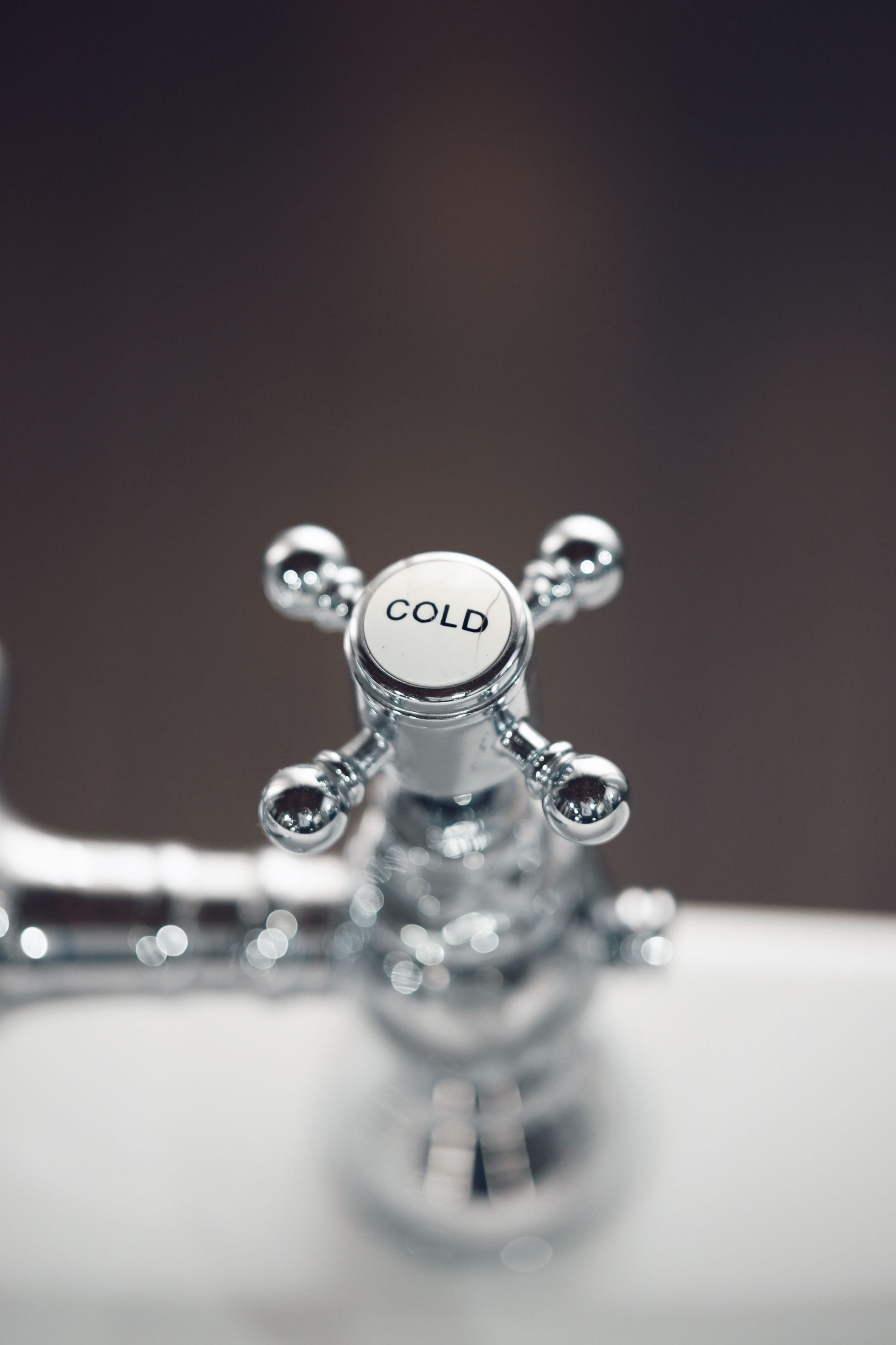 Elegant close-up of a chrome bathroom faucet with a cold water handle, offering a modern touch.